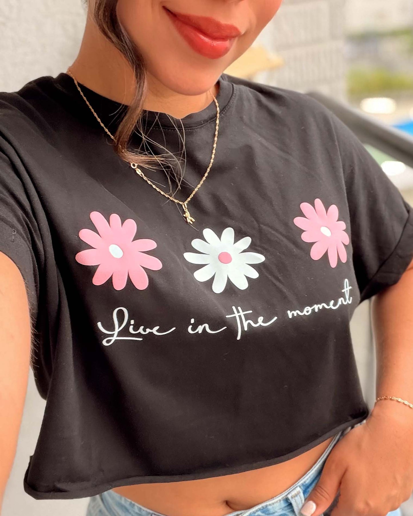 Modelo luciendo camiseta crop negra con diseño floral, estilo juvenil y casual, calidad premium en algodón suave de Mozzaar.