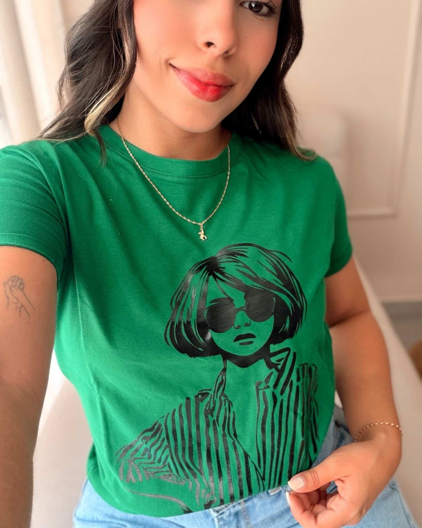 Modelo luciendo camiseta verde de mujer con estampado de chica chic con gafas, estilo urbano y casual, calidad premium de la marca Mozzaar.