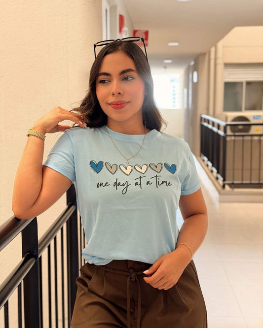 Camiseta azul pastel para mujer con frase "One Day At A Time", marca Mozzaar, estilo regular fit en algodón suave.