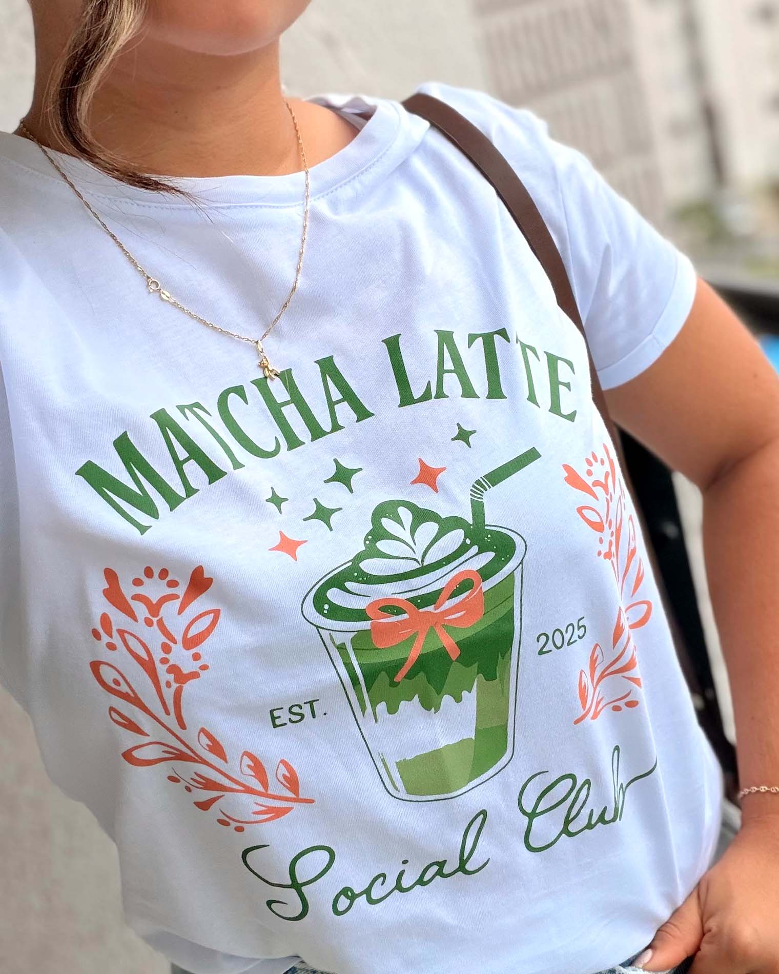 Modelo luciendo camiseta blanca de estilo "aesthetic" con diseño de bebida matcha, calidad premium marca Mozzaar.