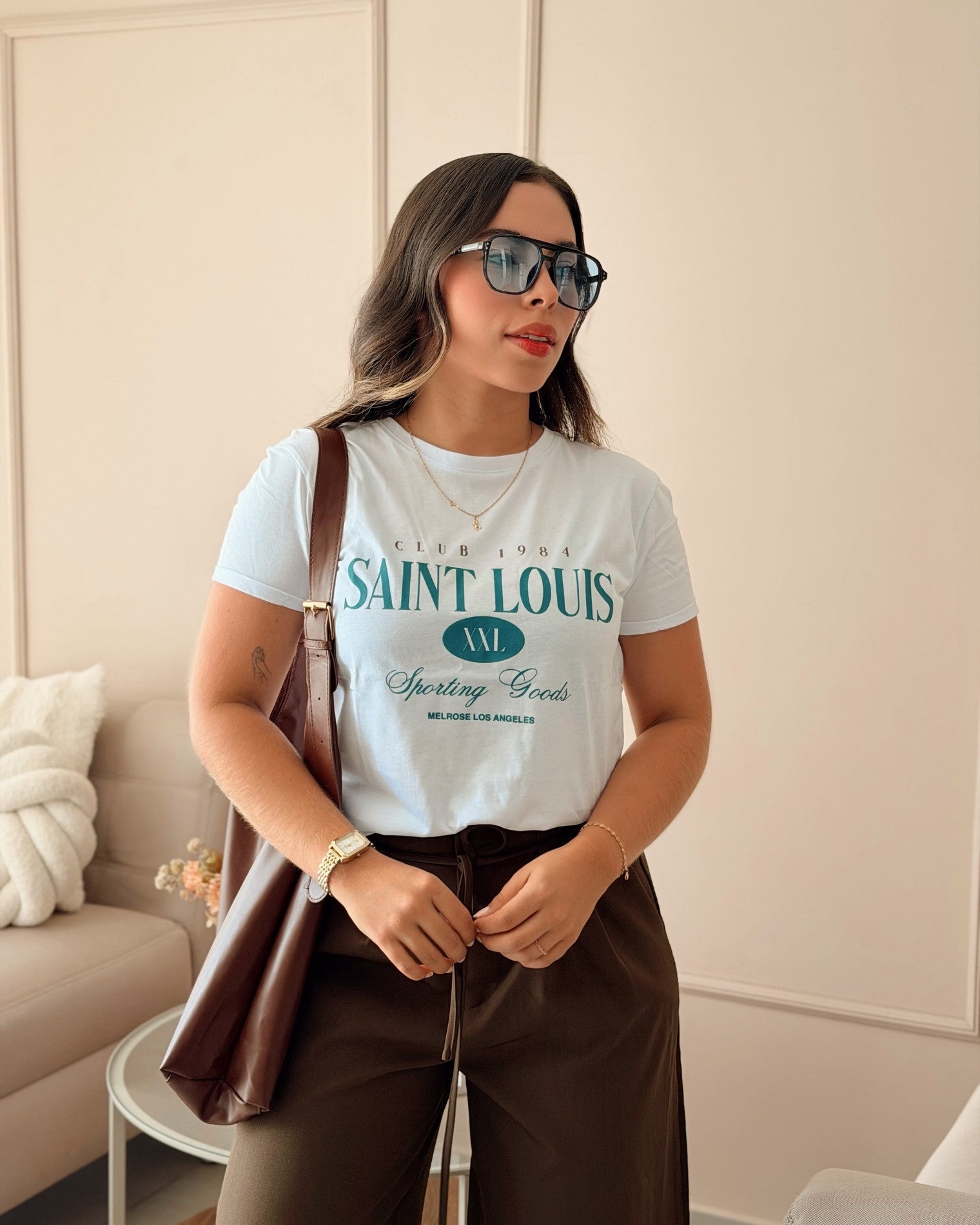 Modelo luciendo camiseta blanca de mujer con diseño clásico "Saint Louis", estilo urbano y versátil para el día a día, calidad superior en algodón de la marca Mozzaar.