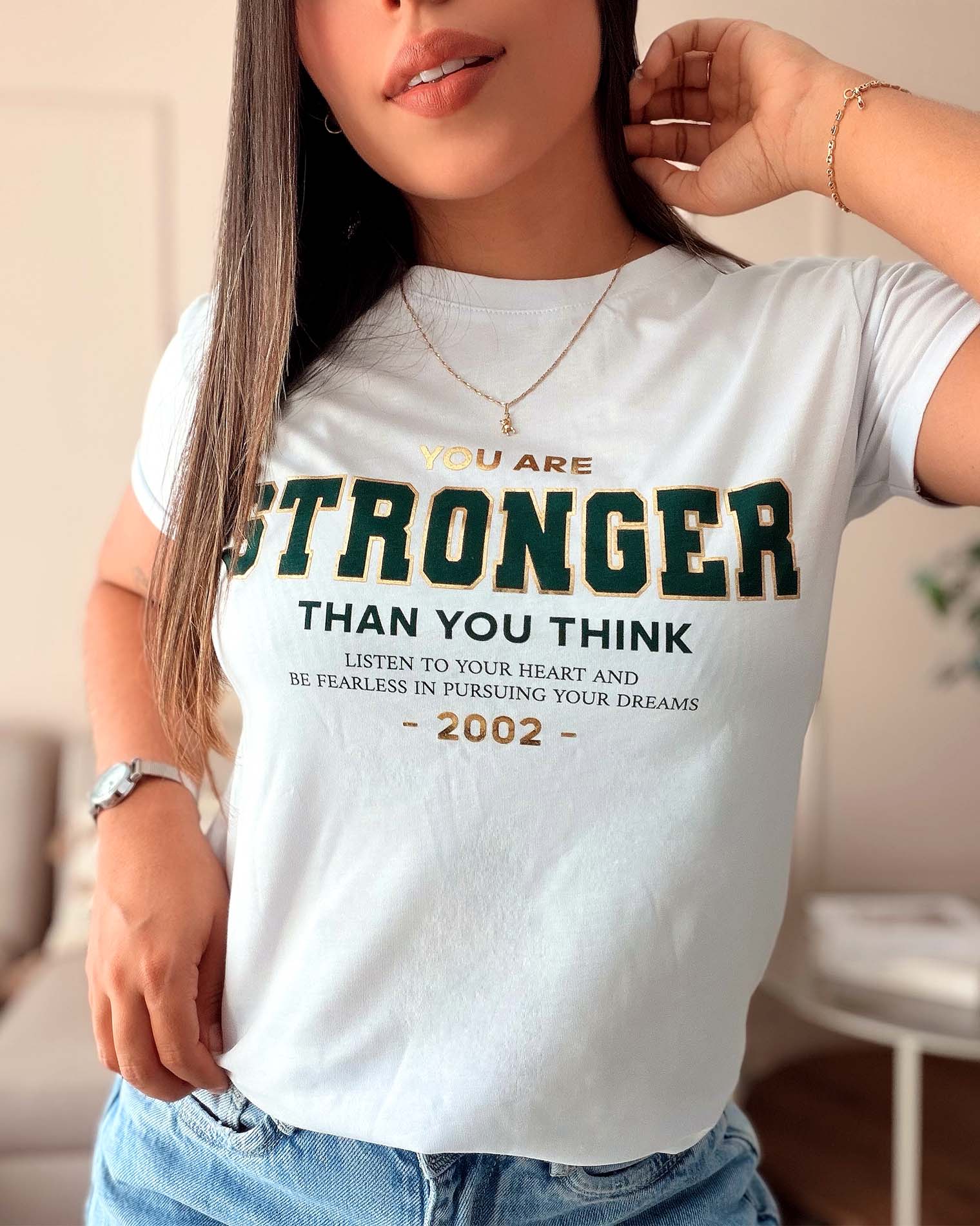 Modelo luciendo camiseta blanca inspiradora de mujer, estilo casual con mensaje positivo, calidad premium marca Mozzaar.