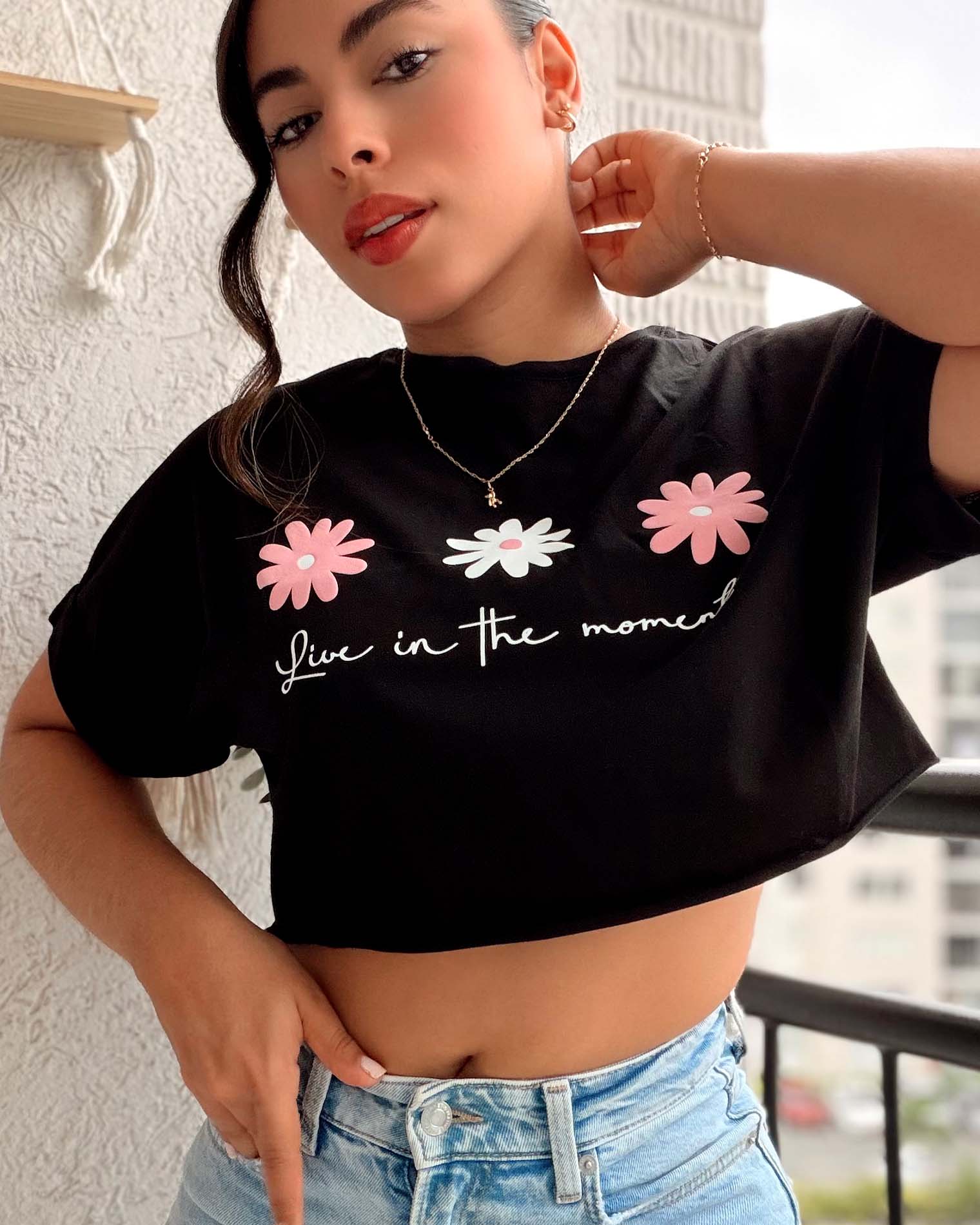 Camiseta negra silueta corta para mujer con estampado de margaritas y frase Live in the moment, marca Mozzaar, 100% algodón Pima.