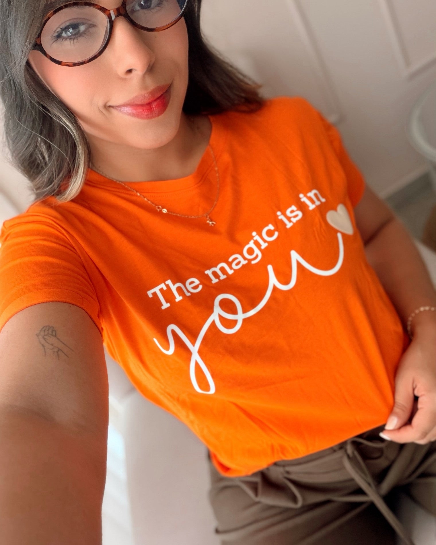 Modelo luciendo camiseta naranja de mujer con mensaje positivo "Magic is In You", estilo urbano y casual para el día a día, calidad premium de la marca Mozzaar.